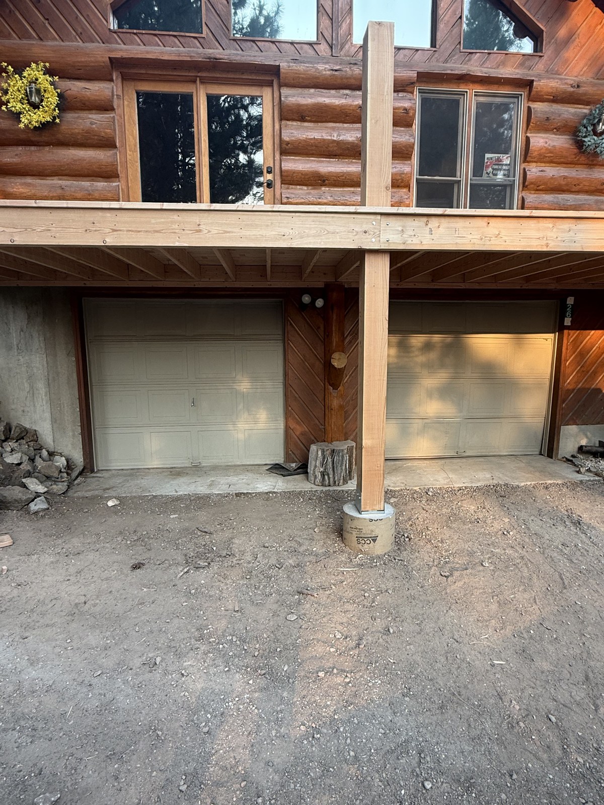 Two new black garage doors installed on a log cabin home